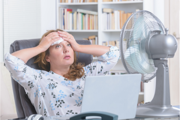 Woman in front of fan with cloth on her head