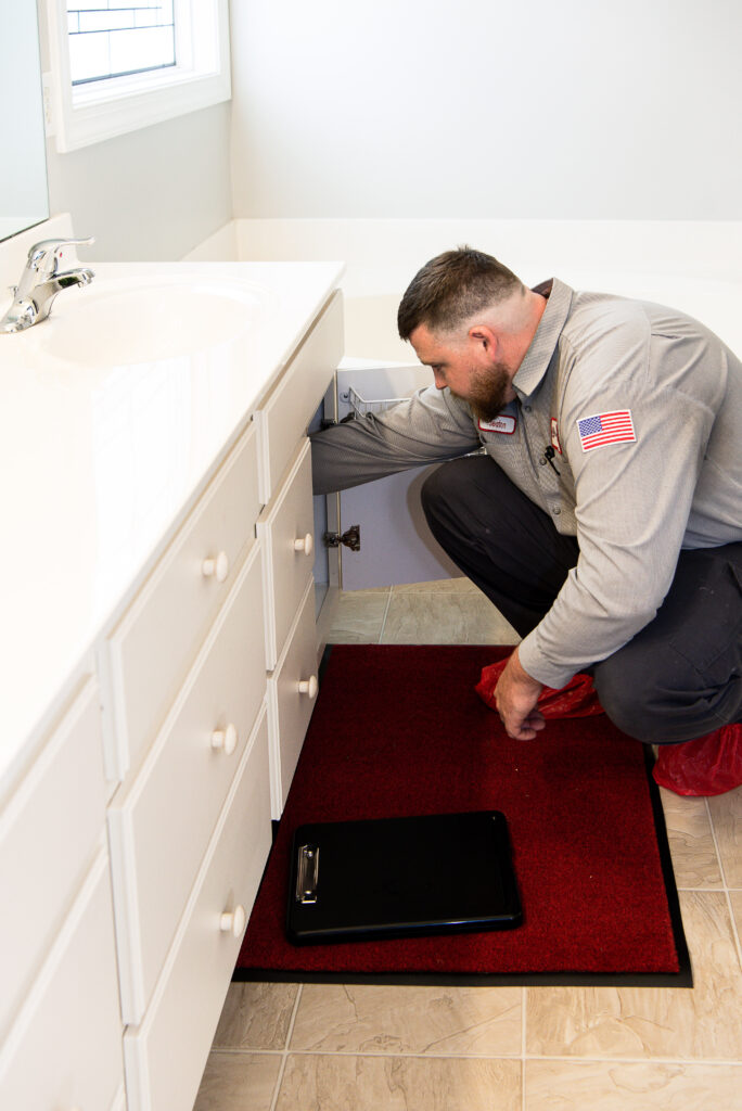 jd service now plumber inspects the drain underneath a bathroom sink in a house
