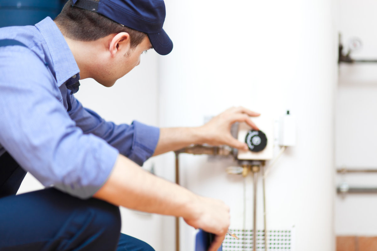 Technician adjusting temperature on water heater